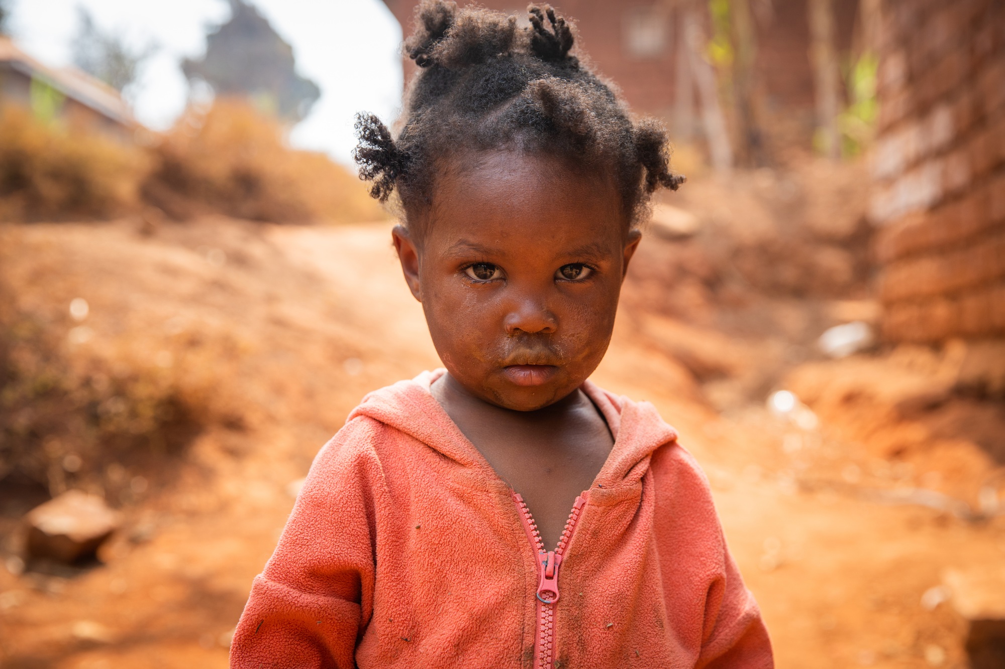 Poor little girl wearing dirty clothes in an African village, poverty and crisis concept. Poor little girl wearing dirty clothes in an African village, poverty and crisis concept.